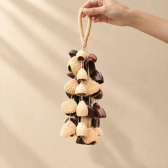 Hand holding a handmade handheld ensemble seed chime blending cream and dark brown natural seeds