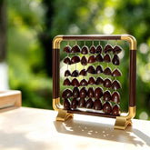 Ember Path — light walnut aluminum frame with gold corner accents, five strings of 15 large deeply textured whole nut seeds (4-5cm each), clear backlight on a wood desk