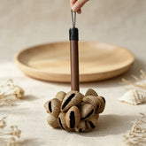 Handmade seed pod rattle held in hand — dried natural seed pods on a wooden handle