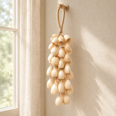 Handmade tano phoenix egg seed chime with ivory seeds hanging by a sunlit window