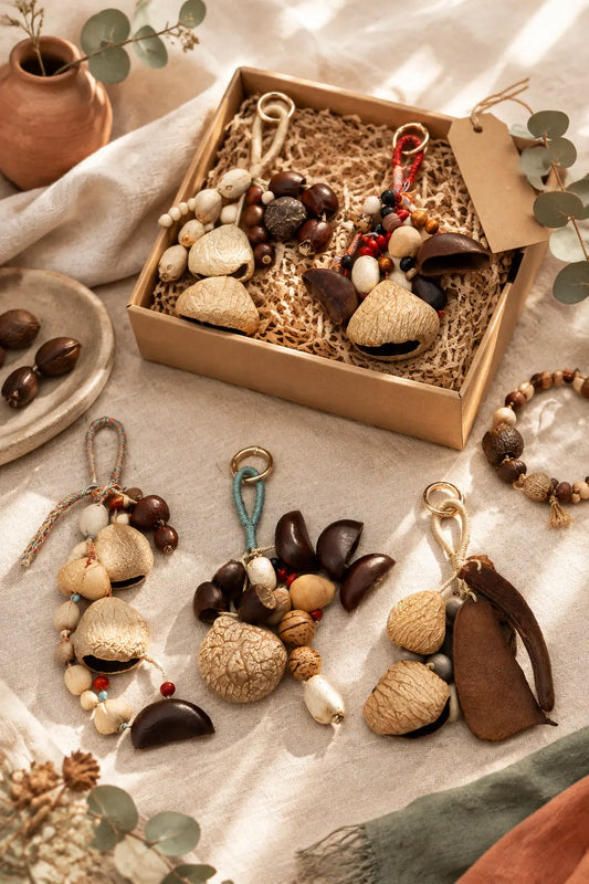 Handmade natural seed wind chime, seed necklace and phone charm arranged as a calming mindful gift on cream linen.
