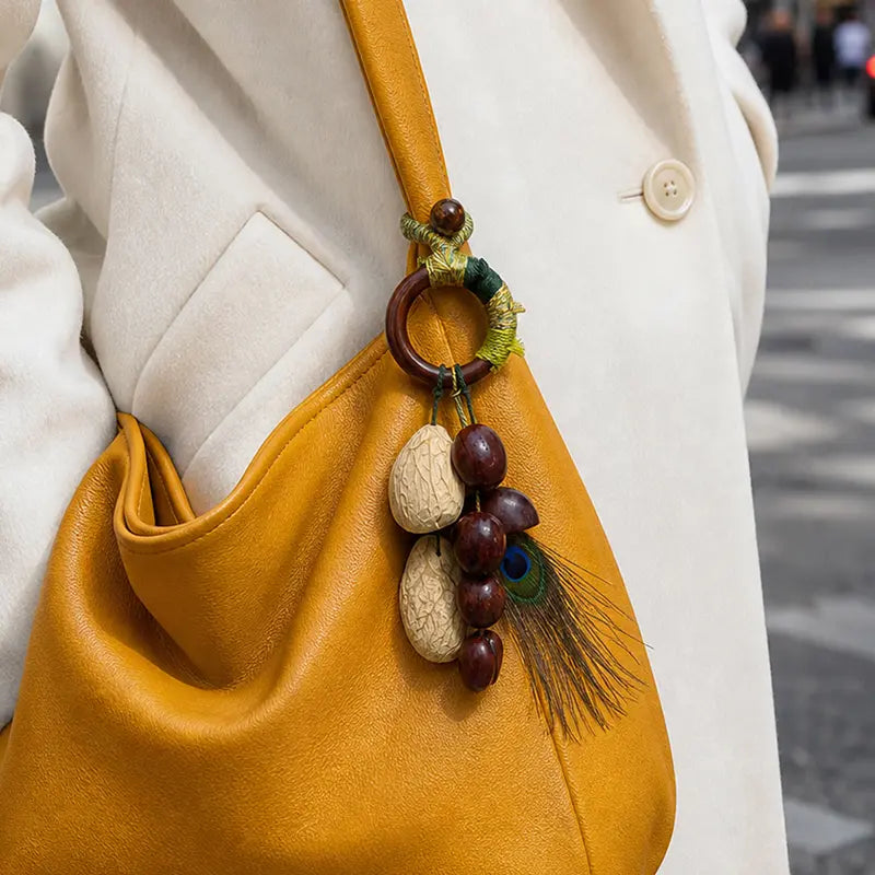 Mustard yellow leather crossbody with artisan seed bag charm and peacock feather
