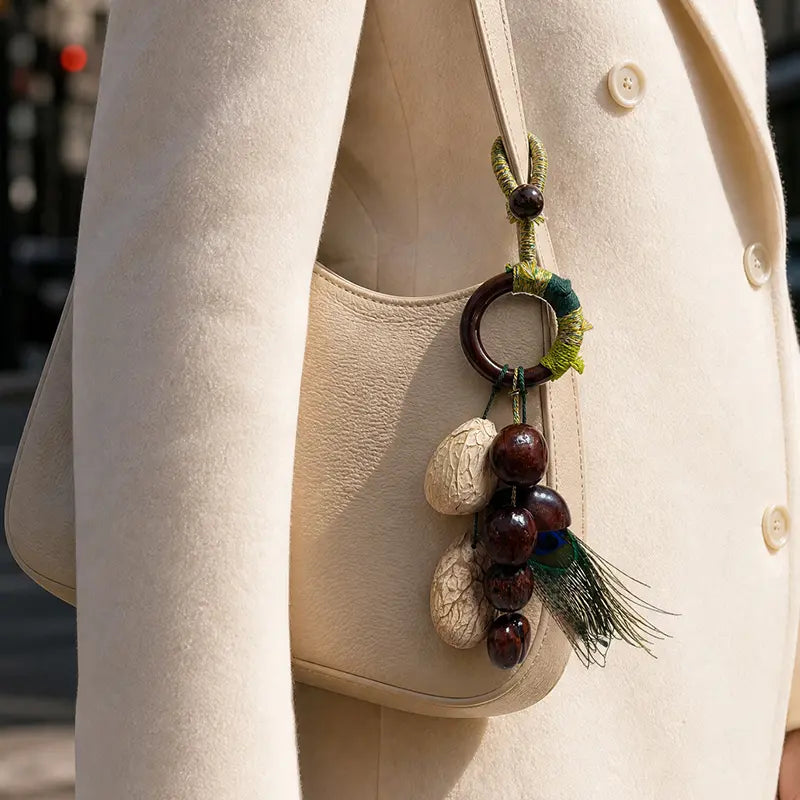 Minimalist cream leather bag with natural seed charm and peacock feather detail