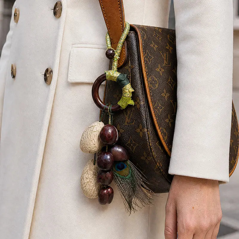 	Natural seed and peacock feather bag charm on designer crossbody bag, bohemian handbag accessory