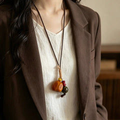 Harvest Pumpkin natural seed necklace — amber pumpkin-shaped nut with red and green beads, handmade boho pendant on adjustable cord