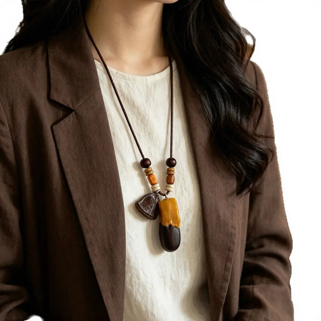 Ebony Duo natural seed necklace — glossy ebony seed paired with a honey-colored amber drop, handmade boho pendant on adjustable cord