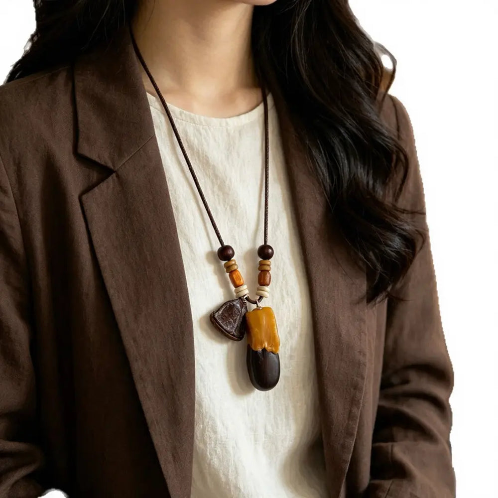 Ebony Duo natural seed necklace — glossy ebony seed paired with a honey-colored amber drop, handmade boho pendant on adjustable cord