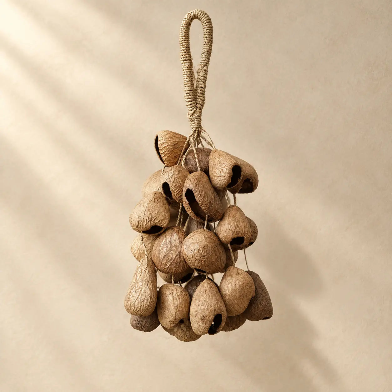 Handmade black fruit shell hanging chime with 30 dark nut shells clustered on natural fiber rope loop, earthy boho decor