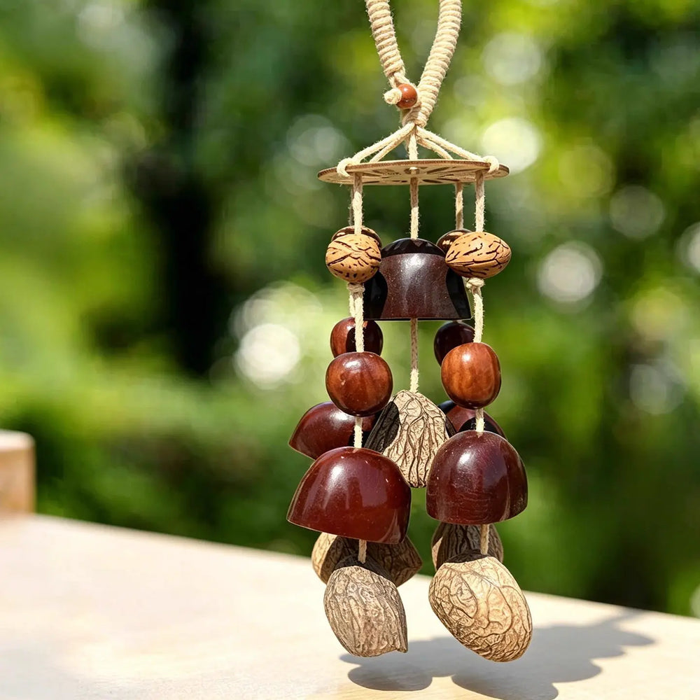 Forest canopy seed wind chime with blue beads, dark polished pod bells and ivory nuts on a white background