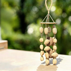 Handmade wind chime on colorful braided cords with layered cream and brown natural seeds under a wooden disk