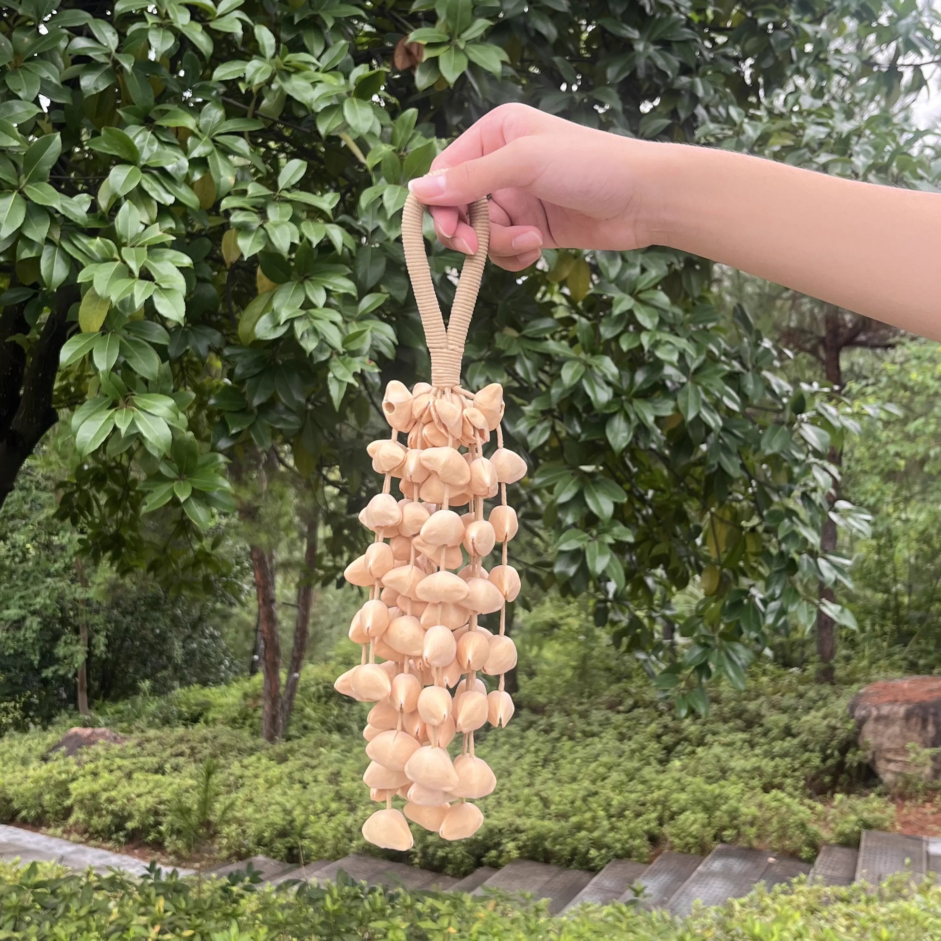 Oleander seed wind chime beside an open window, its soft high chimes carried by a gentle breeze