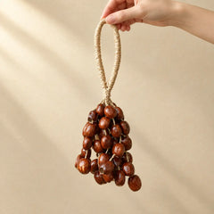 Hand holding a handmade handheld pala cardamom seed chime with small light golden-brown seeds