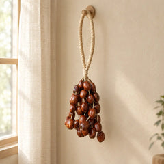 Handmade pala cardamom seed wind chime hanging in a bright window with flowing curtains