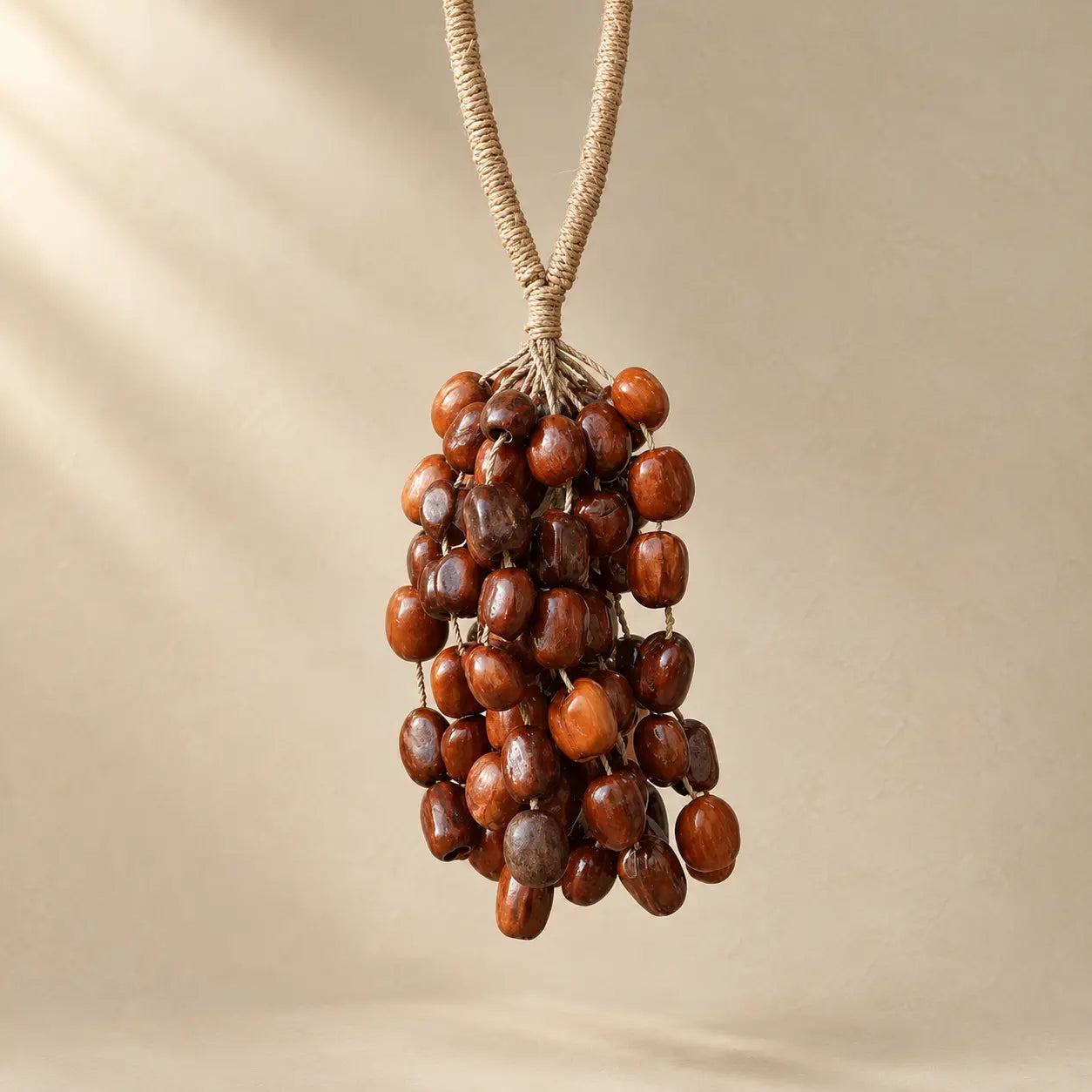 Handmade Pala seed hanging chime with 98 polished reddish-brown seeds clustered on natural fiber rope, warm boho sound decor