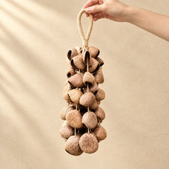 Hand holding a handmade handheld panji pangium edule seed wind chime with dark brown nuts