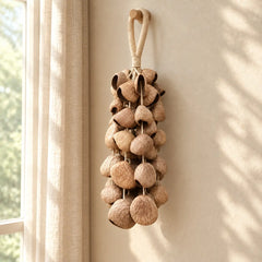 Handmade panji pangium seed chime with dark brown nuts hanging by a softly lit window