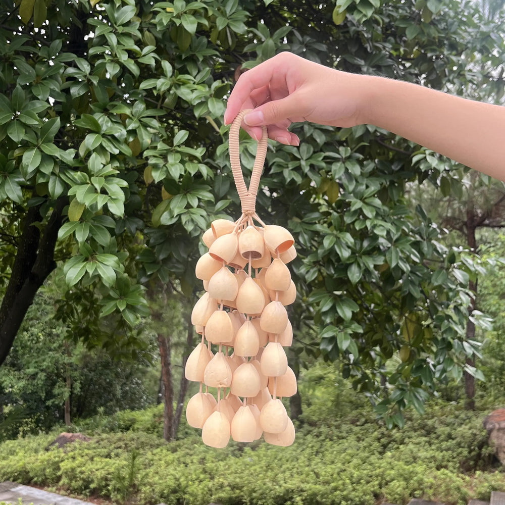 Phoenix egg seed wind chime hanging on a green balcony, a handmade natural chime for outdoor relaxation