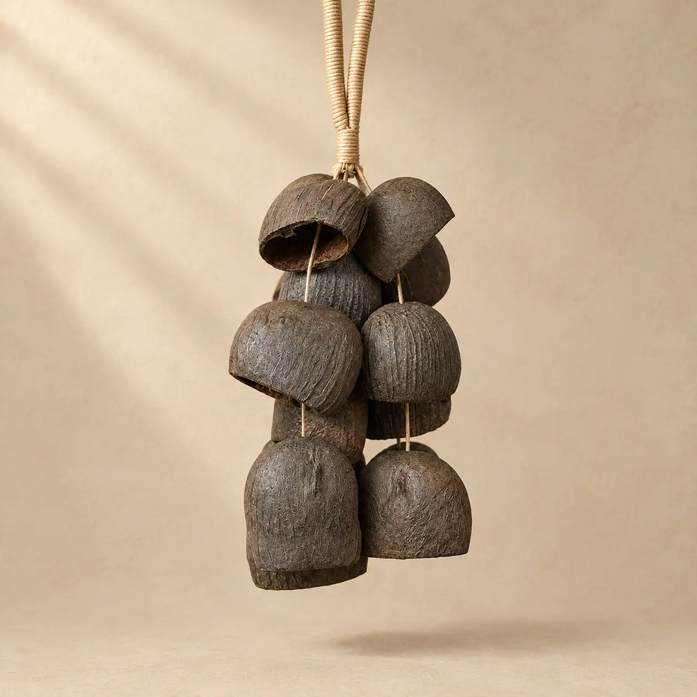 Salin coconut shell wind chime with 15 half coconut shells on natural fiber rope, earthy brown, hanging against beige wall