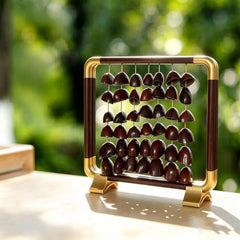 Ember Path — light walnut aluminum frame with gold corner accents, five strings of 15 large deeply textured whole nut seeds (4-5cm each), clear backlight on a wood desk