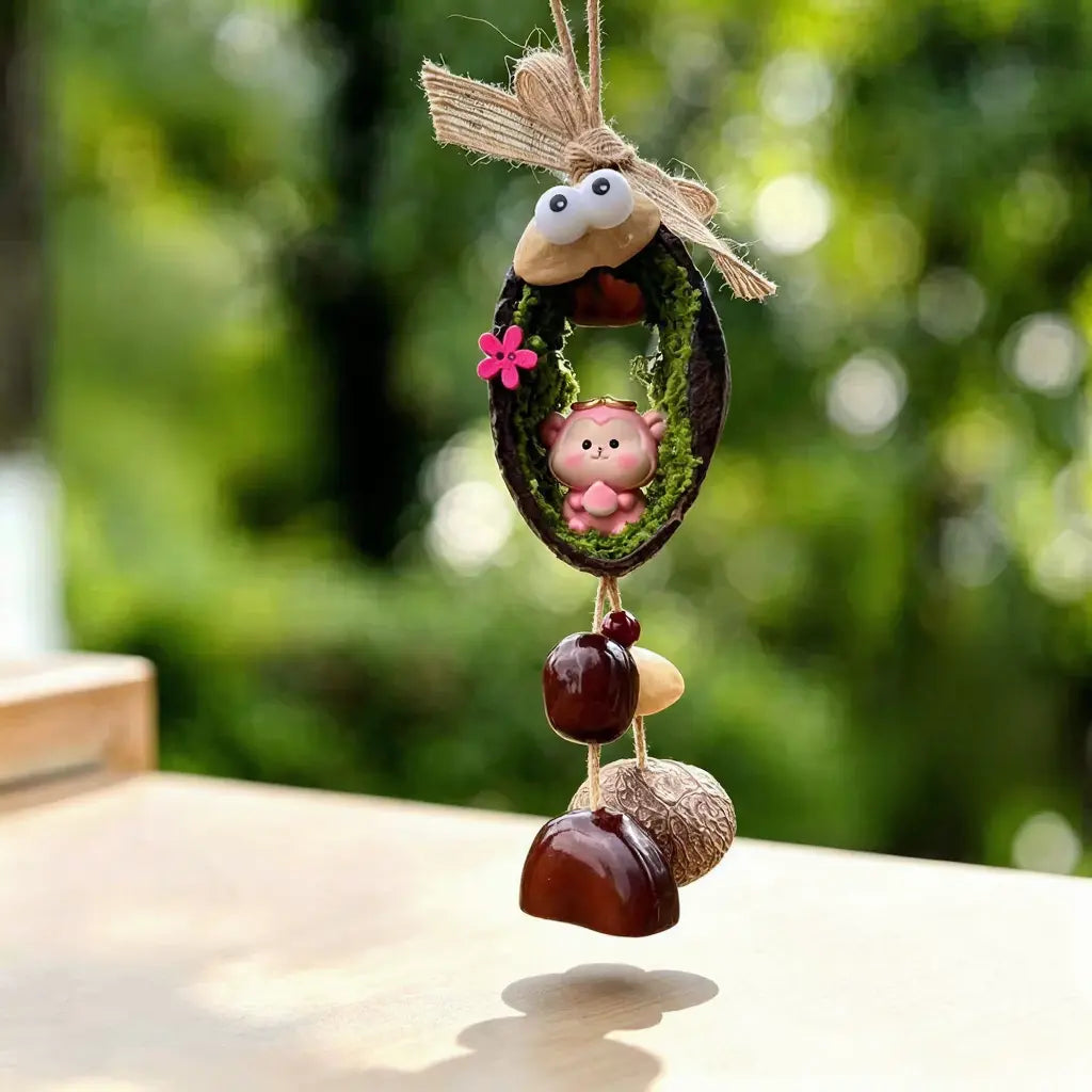 Monkey zodiac chime — pink monkey with gold crown holding a peach in a mossy nut shell nest
